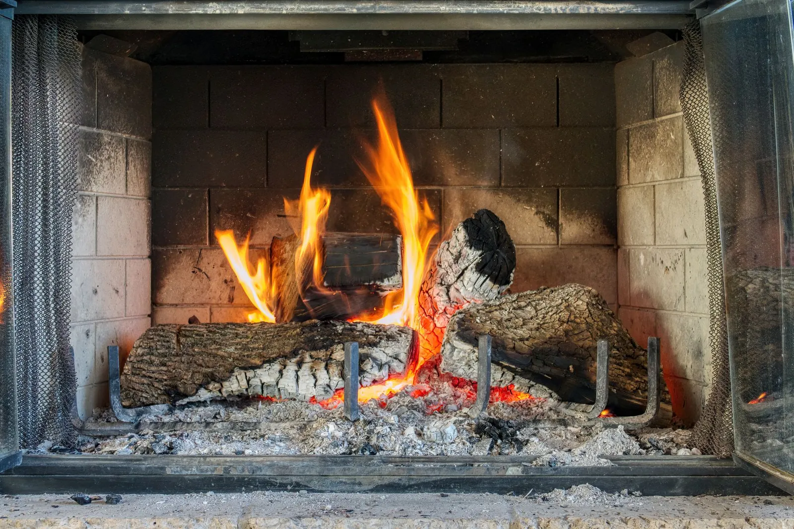 Log fire burning on a grate inside a firebrick-lined open fireplace